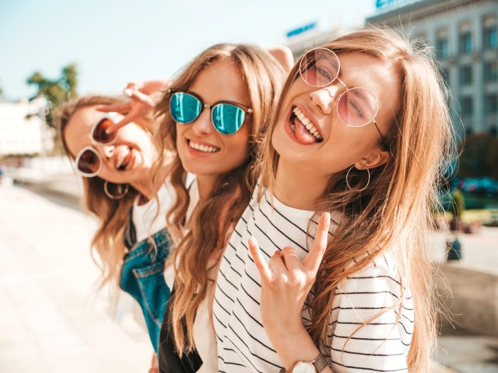 Portrait of three young beautiful smiling hipster girls in trendy summer clothes. Sexy carefree women posing on the street background.Positive models having fun in sunglasses.Hugging